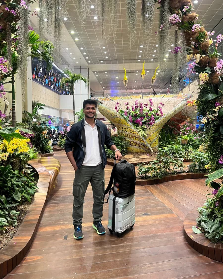 Sandeep with a suitcase in a garden atrium at Singapore airport